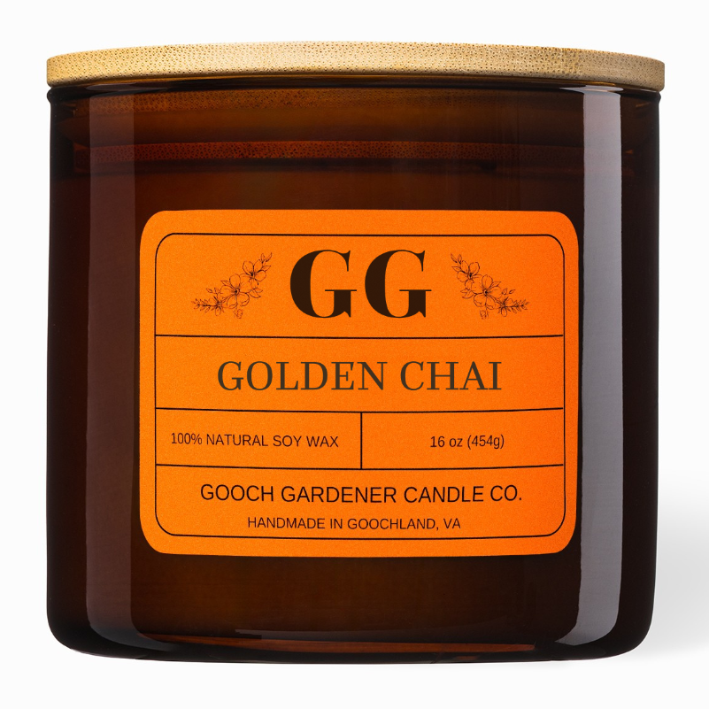 An amber glass jar candle with a light wood lid and a bright orange label reading &