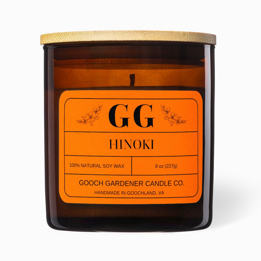 Candle with orange label featuring 'GG Hinoki' on a white background