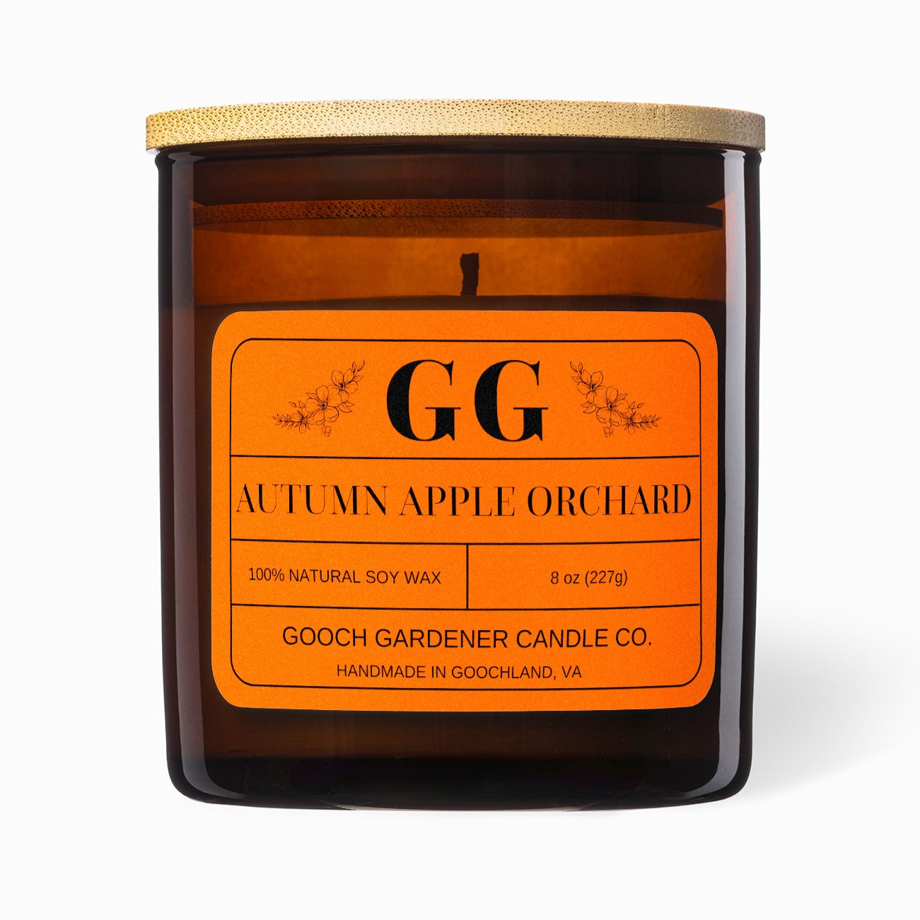 Candle with orange label featuring 'GG' branding on a white background