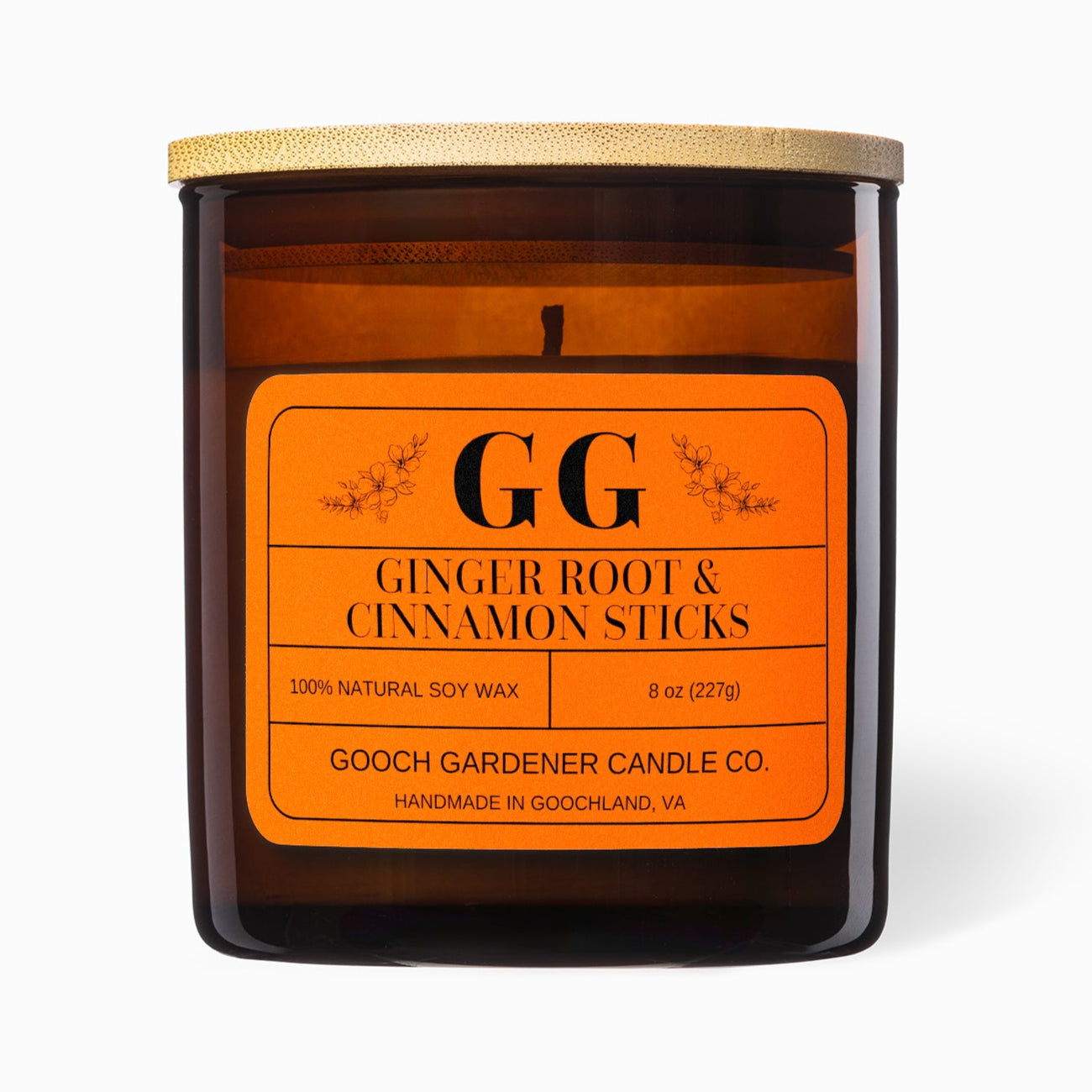 Ginger Root & Cinnamon Sticks candle with orange label on a white background