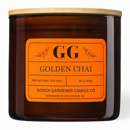 An amber glass jar candle with a light wood lid and a bright orange label reading &