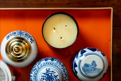 Collection of ceramic items including teapots and a candle on an orange tray.
