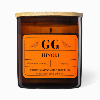 Candle with orange label featuring 'GG Hinoki' on a white background